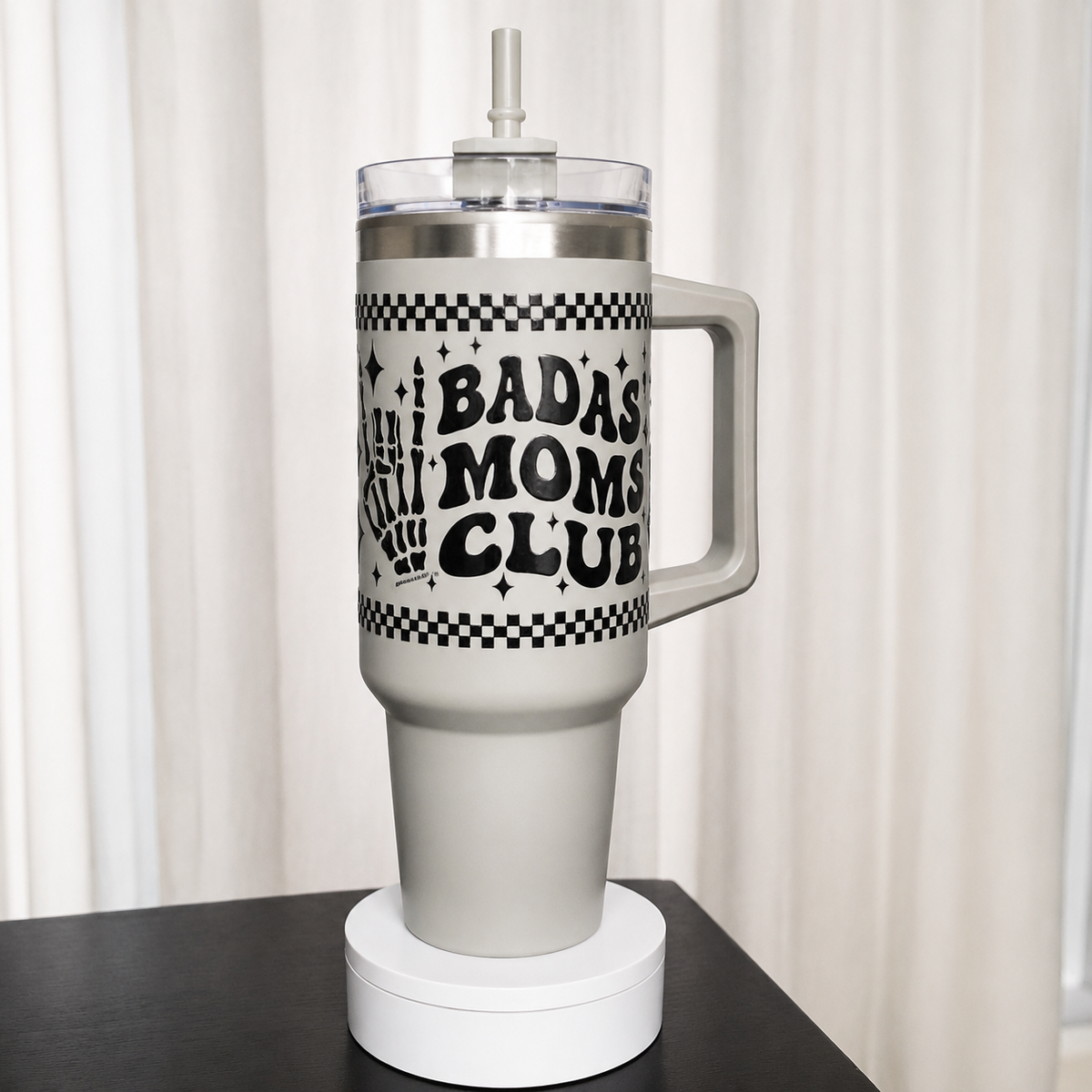 Grey tumbler with 'Badass Moms Club' text on a black surface